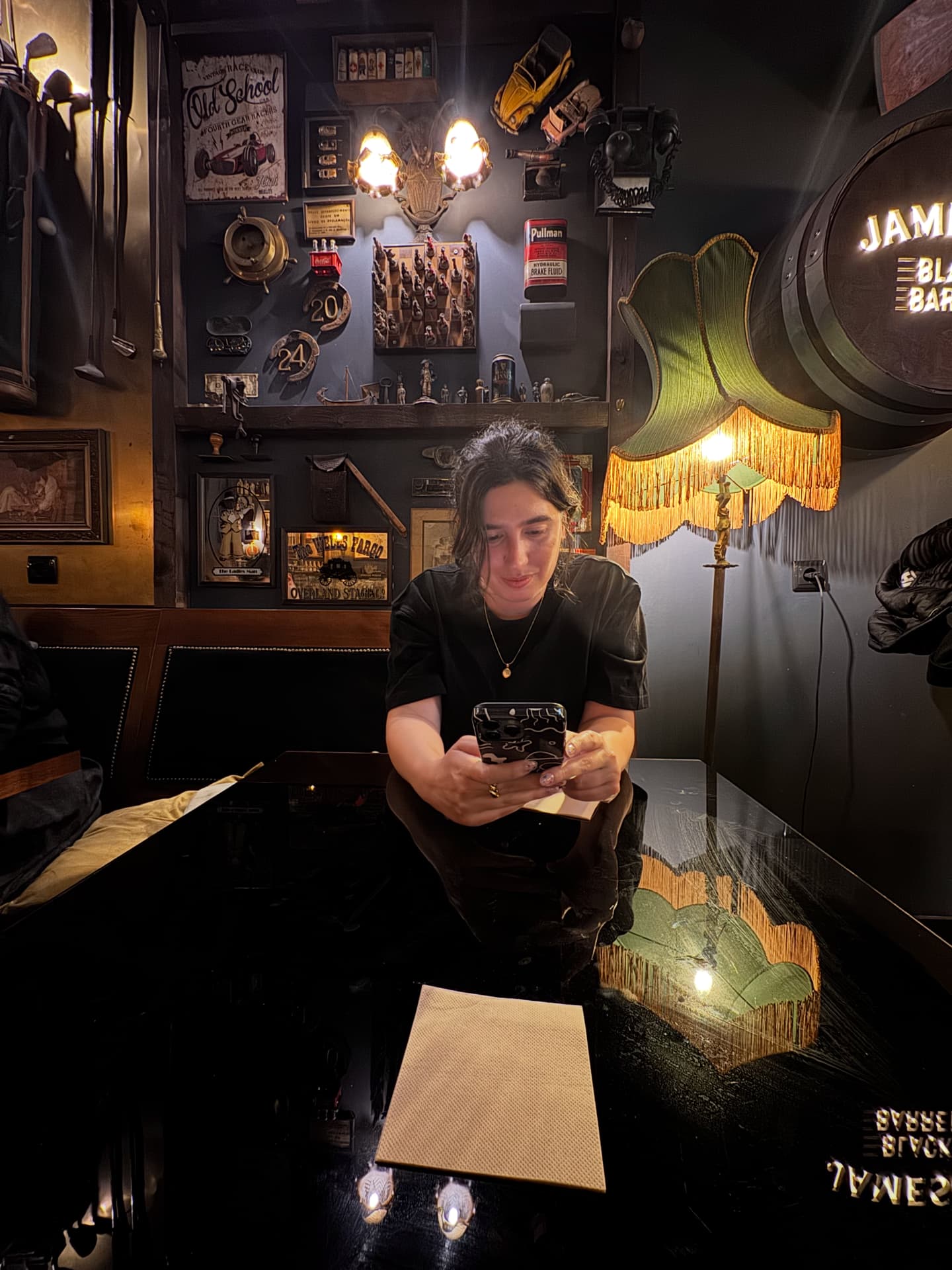 Nina distracted with her phone in a local pub while waiting for drinks.